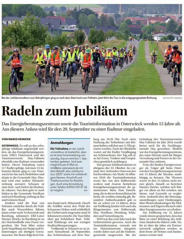 Eine Gruppe von Radfahrern mit Warnweste und Fahrradhelm radelt zum Fallstein. Im Hintergrund sind die Häuser eines Dorfes zu sehen.