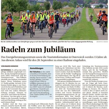 Eine Gruppe von Radfahrern mit Warnweste und Fahrradhelm radelt zum Fallstein. Im Hintergrund sind die Häuser eines Dorfes zu sehen.
